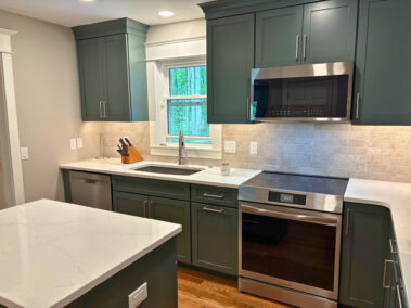 Sage green kitchen with quartz countertops, new stainless appliances and accents